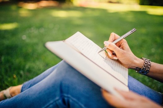 girl writing in notebook outdoors