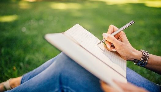 girl writing in notebook outdoors