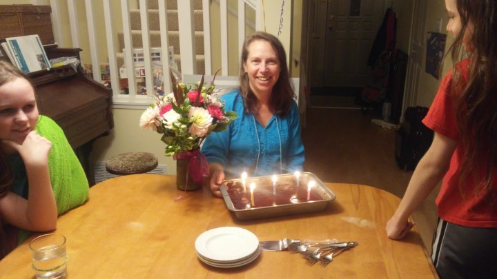 Sheila with birthday cake and bouquet of flowers