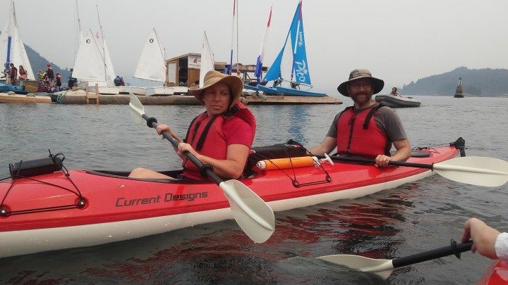 Sheila and Emile kayaking with sailboats on dock in background